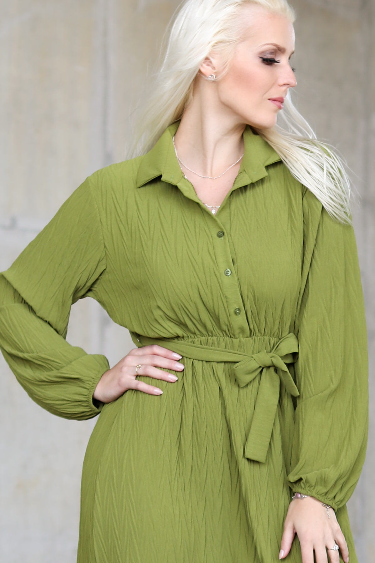 Zielona sukienka z marszczonego materiału wiązana w pasie
